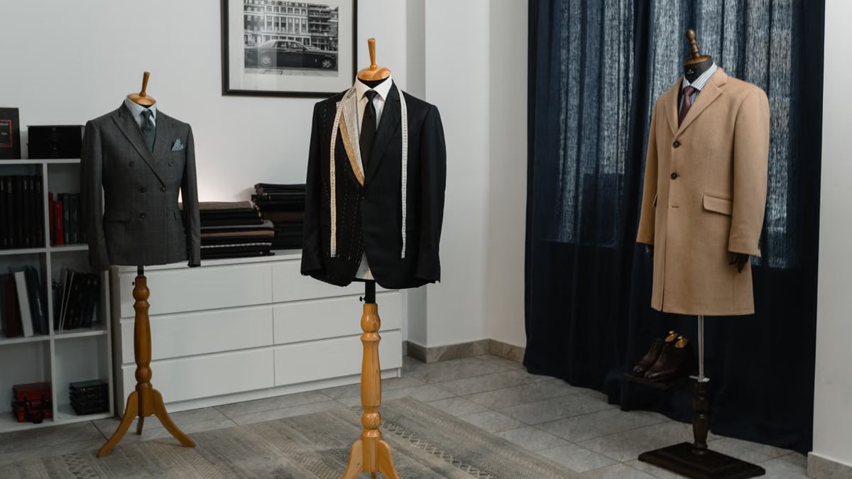 Stylish men's suits on mannequins in an atelier, showcasing luxury tailoring.
